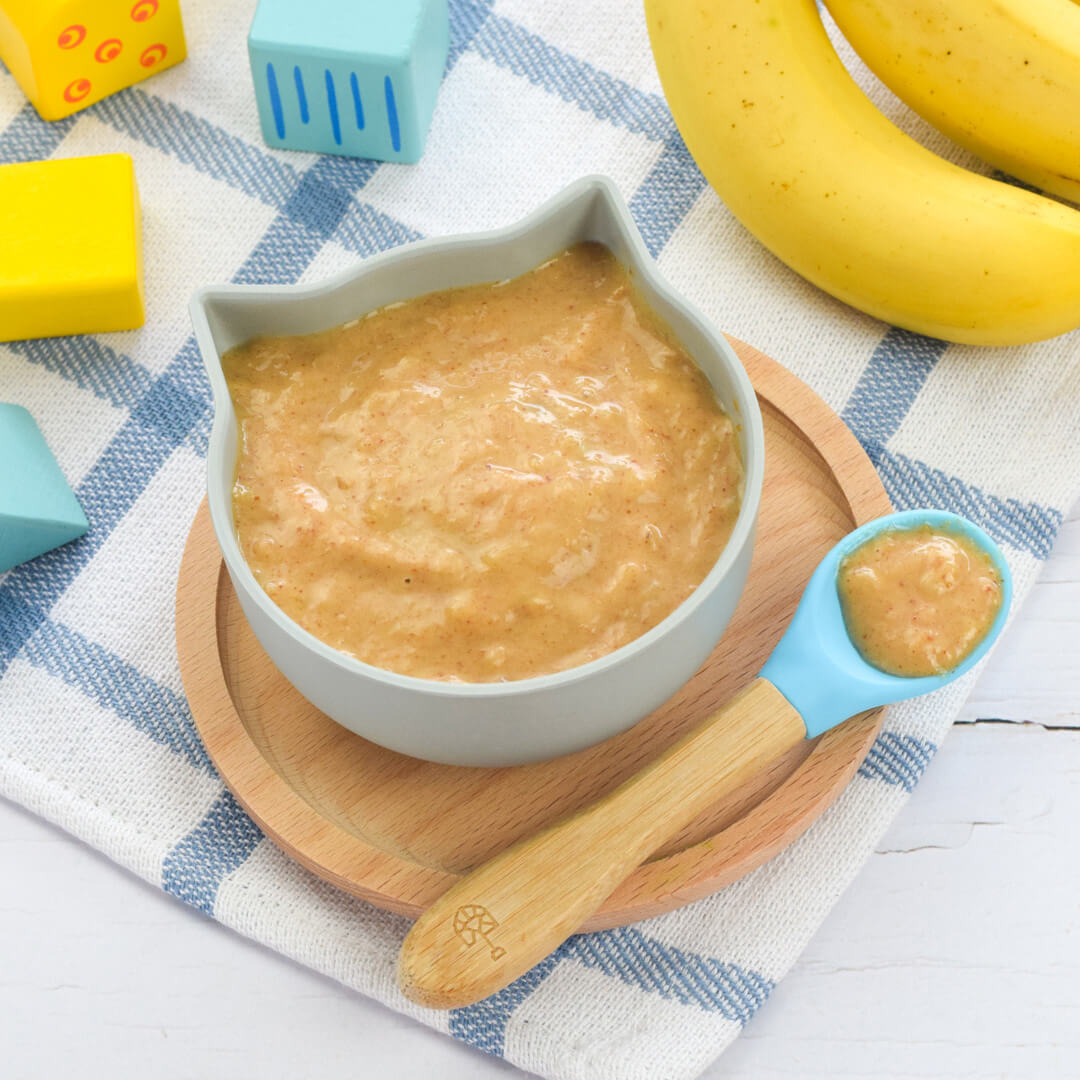 A bowl of peanut butter & banana puree, next to 2 bananas