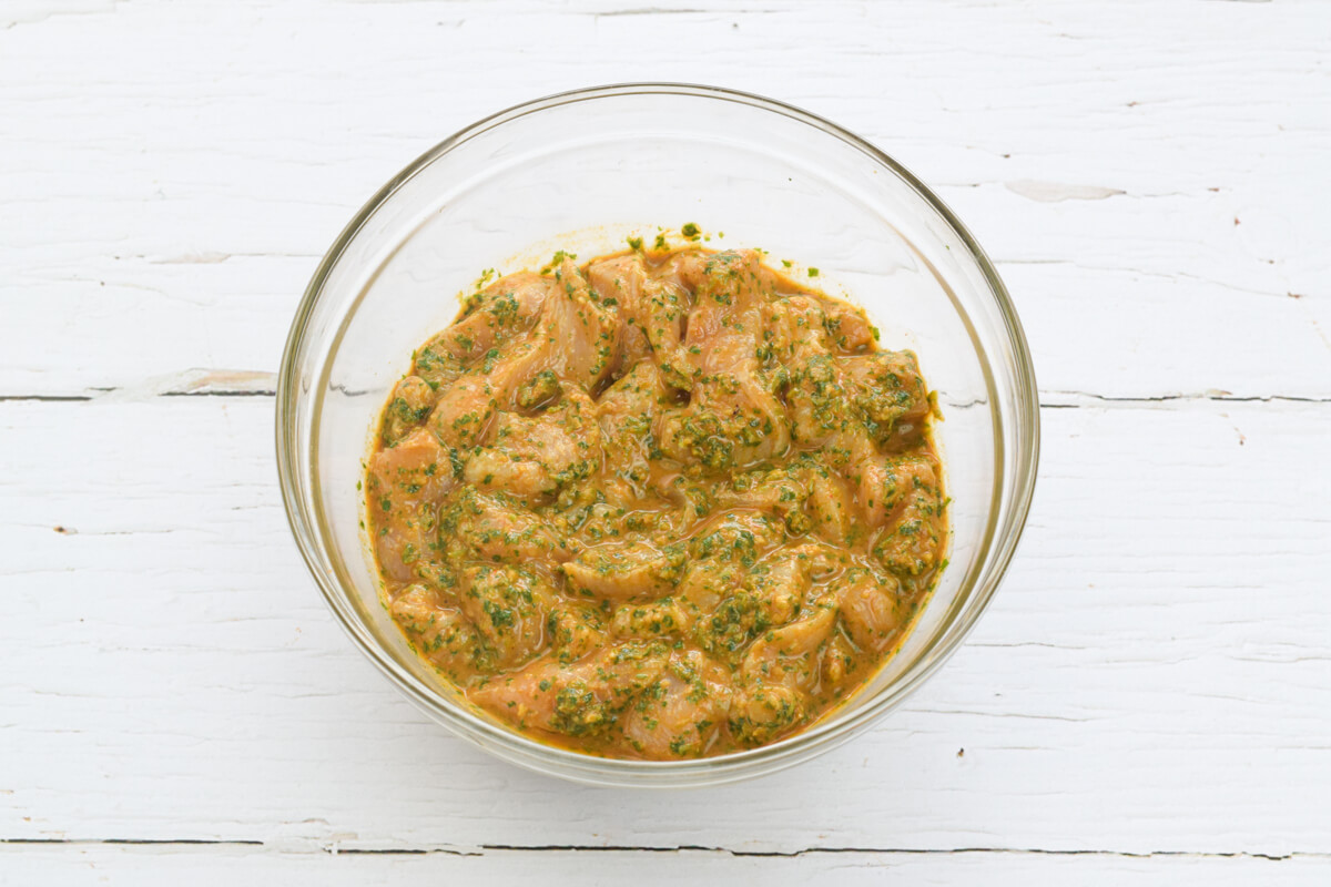A glass bowl with chicken in a marinade