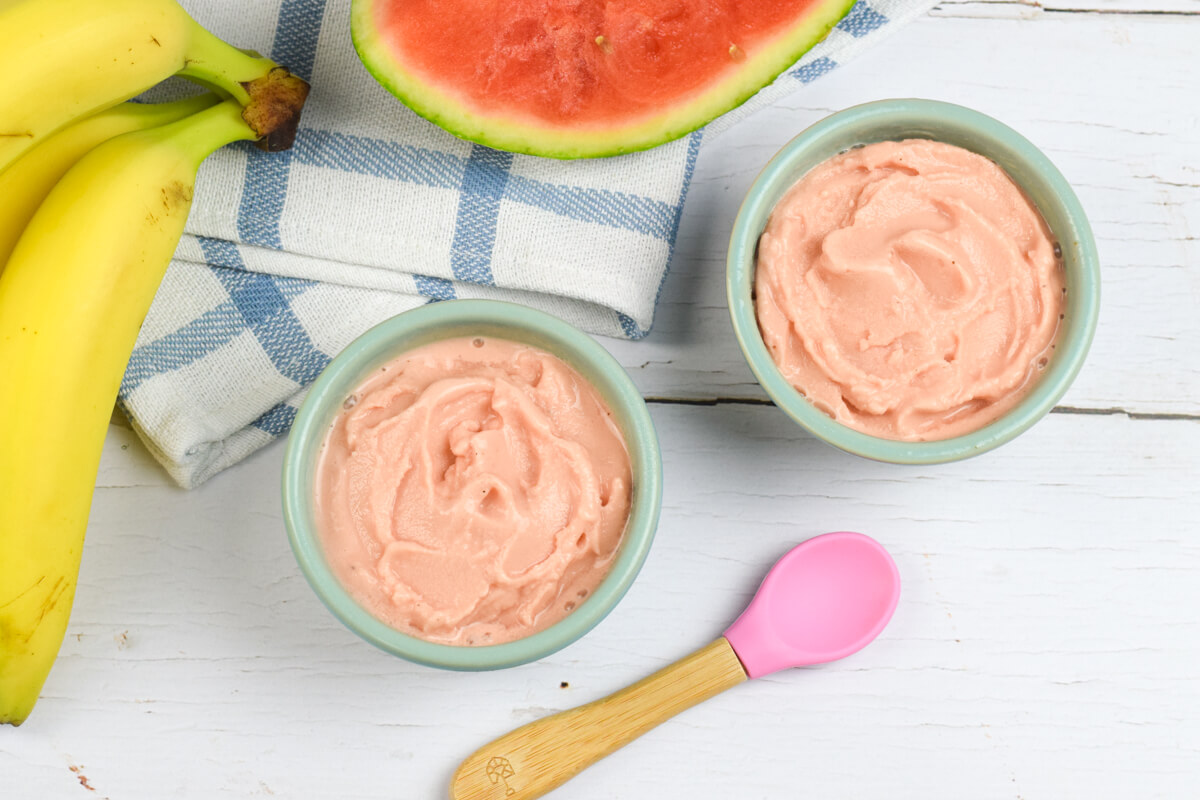 2 small bowls of watermelon nice cream next to a sliced watermelon and some bananas